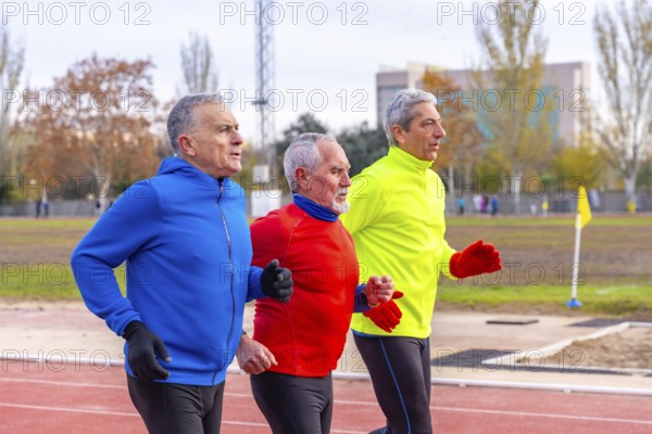Senior sportive men with colorful sports clothes running together in an athletics field