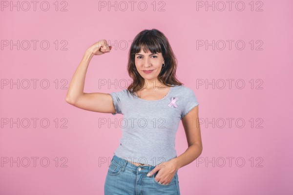 A woman wearing pink breast cancer awareness ribbon while showing arm muscle. Victory over breast