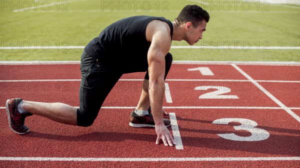 Side view male runner sprinter getting ready start race. High resolution photo