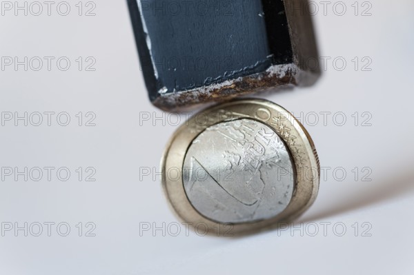 Euro coin with converx curvature under a hammer