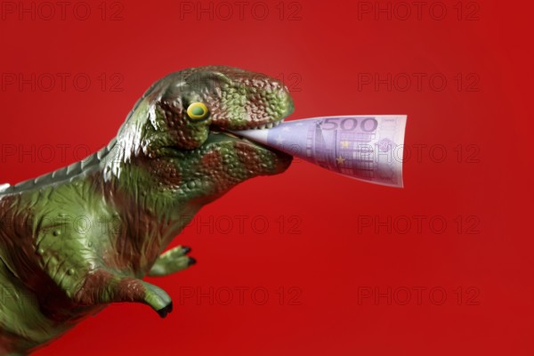 Toy dinosaur with euro note in its yaws over red background