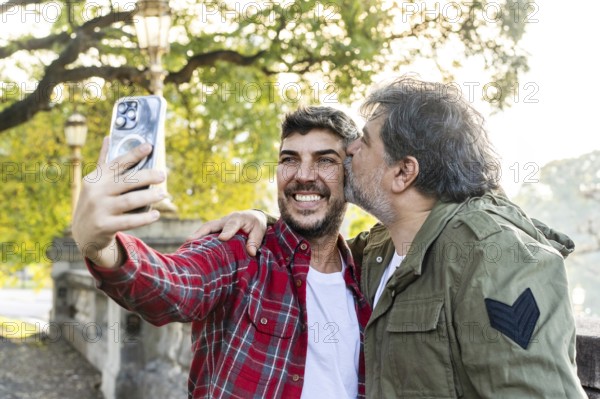 A man is kissing his husband while his husband takes a selfie in that scene