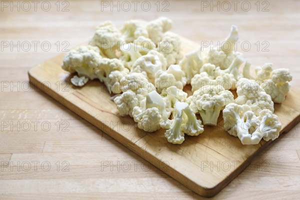 Cauliflower florets on a wooden cutting board, prepared ingredient for cooking a vegetable dish,