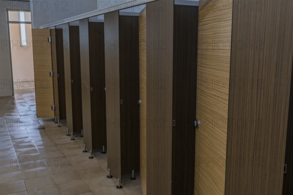 Wood grain doors to toilet stalls in men's public restroom in South Korea