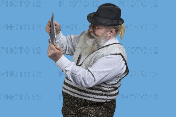 Portrait of excited senior man playing video game on tablet pc. Isolated on blue