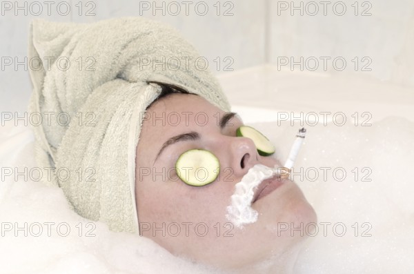 Headshot on a Woman Relaxing in the Bathtub with a Towel on Her Head and Smoking a Cigarette in a