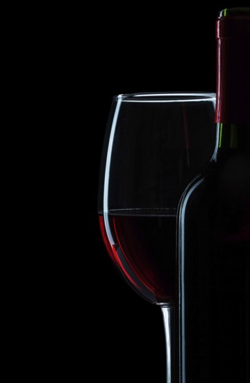 Bottle and wine glass with red wine close-up on white background
