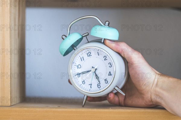 Retro styled white alarm clock in the wooden bookshelf