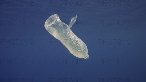 Disposable plastic bottle drift under surface of blue water. A plastic bottle is thrown into sea