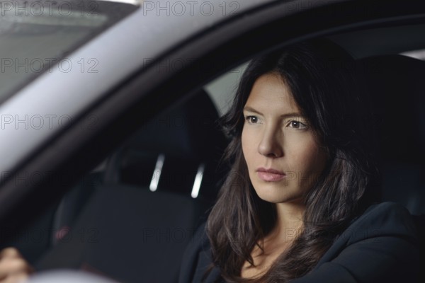 View through the windscreen with reflections of lights of a serious young woman driving her car at