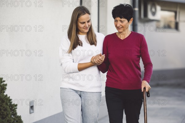 Young caucasian woman a nurse, on a home visit taking care of a senior lady. Nurse helping a senior
