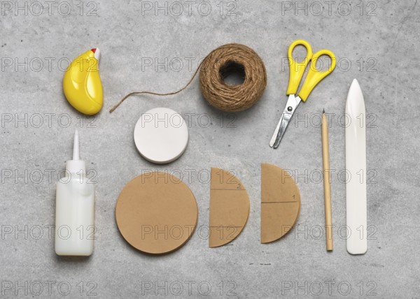 Workplace with craft equipment: brown and white coffee filters, glue, scissors, pencil, jute twine,