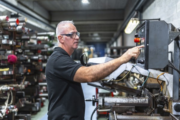 Man operating in the control station of a mechanical saw in a metal cnc factory
