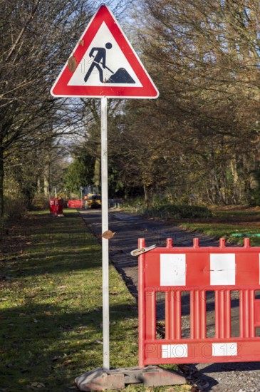 Red and white roadblock and roadworks sign closing a park path for construction
