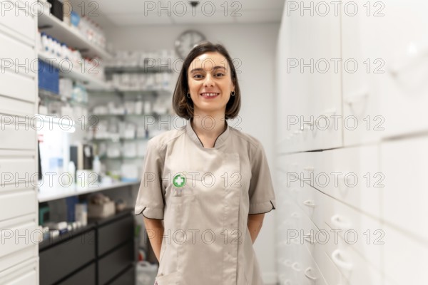 Portrait of a young woman pharmacist standing in the storage room smiling at camera