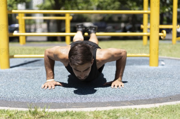 Fit male engaging in a push-up workout at an outdoor gym.
