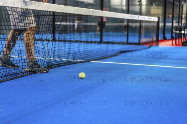 Cropped photo of a tennis ball next to the net while friends playing indoors