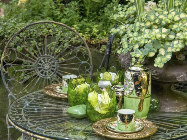 A decorated garden table with green tea service, glasses and plants in the background, borken,