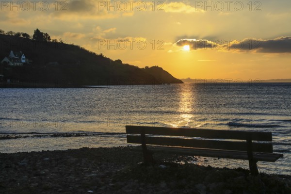 Bench on Le Caro beach shortly in front of sunset, view of the Presqu'ile de Crozon,