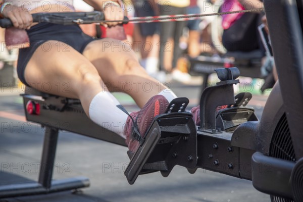 Close-up of a person using a rowing machine in the outdoor gym, focusing on his legs, Barcelona,