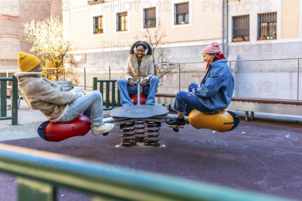 Three friends enjoying a sunny winter day, playing together on a playground seesaw in a city park
