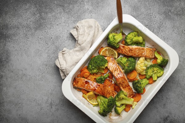 Top view of healthy baked fish salmon steaks, broccoli, cauliflower, carrot in casserole dish on