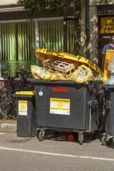 Overfilled waste containers for lightweight packaging standing on the street, Germany, Europe