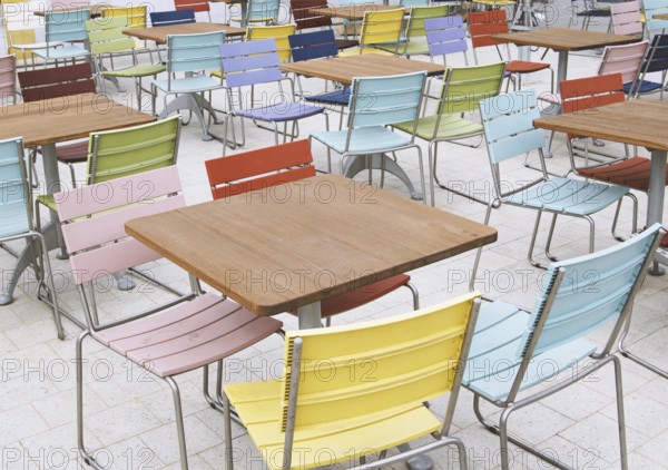 empty deserted street cafe or outdoor restaurant tables with multicolored chairs - off season or