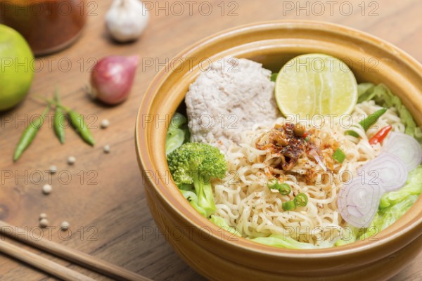 Hot and spicy noodle with pork and vegetables on the wood background
