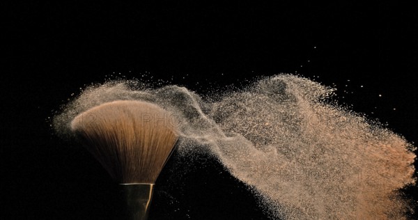 Make-up Brush spreading blush powder on black background