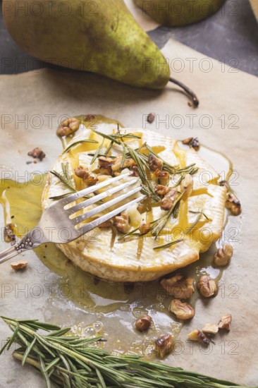 Piece of baked camambert on a fork. Delicious baked cheese with honey, walnuts, herbs and pears