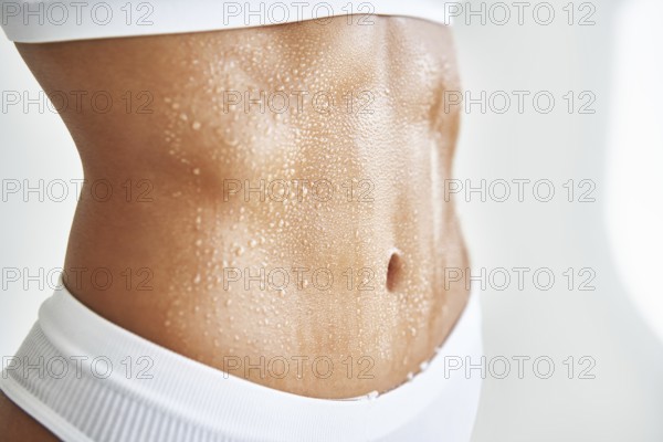 Close up belly of a beautiful sporty girl in drop of sweat or water on skin. Body care, fitness