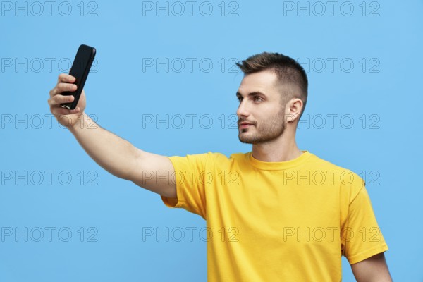 Handsome young man taking selfie over blue background. People concept