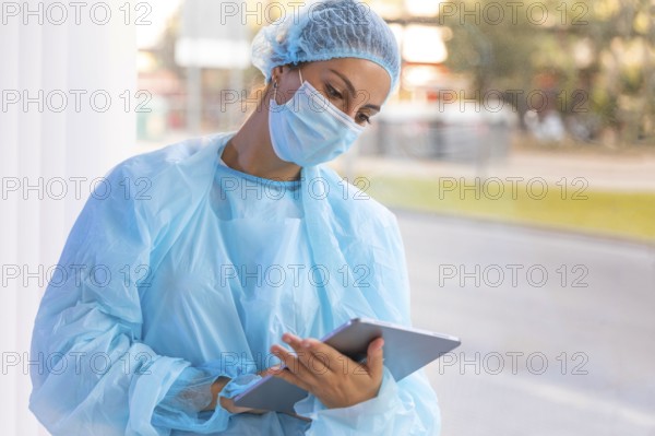 Female doctor protective wear looking clipboard