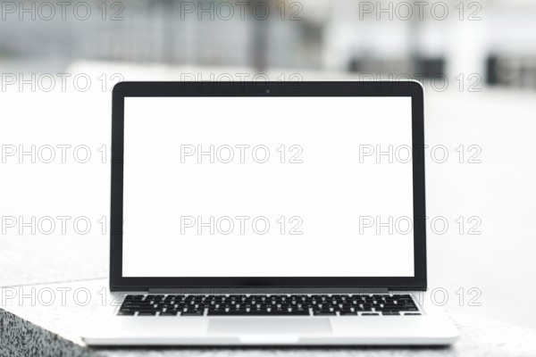 Open laptop showing blank white screen display bench against blurred background. High resolution