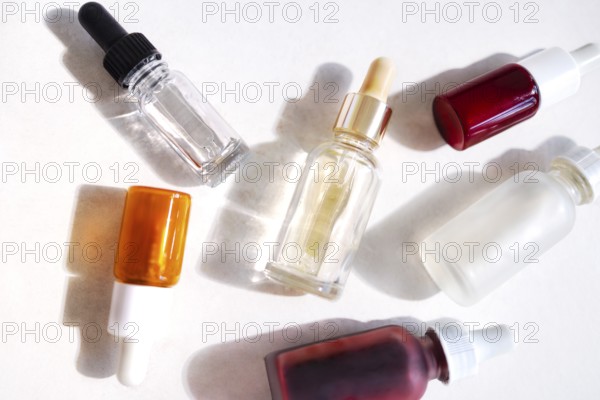 Serum with collagen and peptides in colorful glass bottles on light background with sunlight shadow