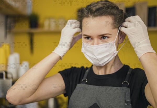 Front view female barista putting medical mask