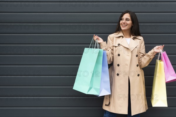 Front view woman with glasses holding lots shopping bags with copy space