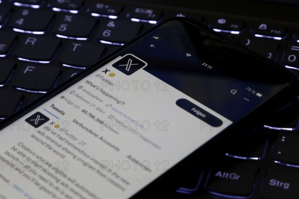 Symbolic image social media, close-up of a smartphone on an illuminated computer keyboard with X