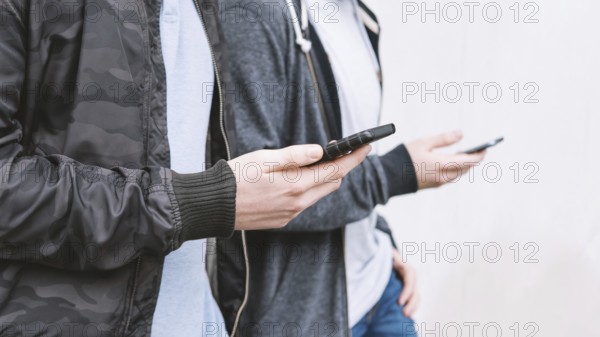 two unrecognizable antisocial mobile phone addicted male teenagers using smartphone, technology