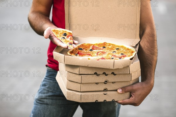 Close up delivery guy holding pizza slice