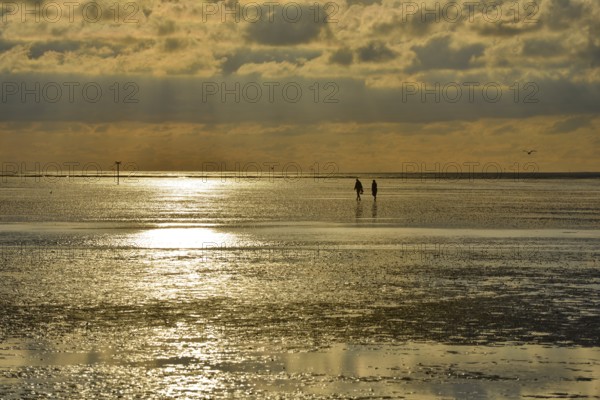 Evening atmosphere, sunset, Wadden Sea, two people walking between Neuwerk Island and