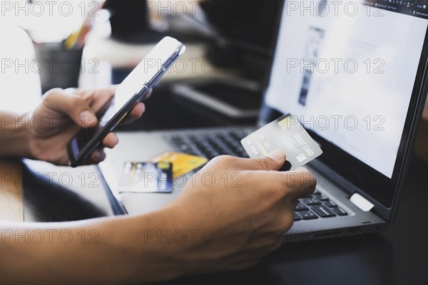 A man online shopping at home using credit card, Mobile phone and laptop for online shopping,