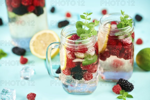 Fresh berries cocktail in glass jar. Fresh summer cocktail with mix of berries, lemon and mint on