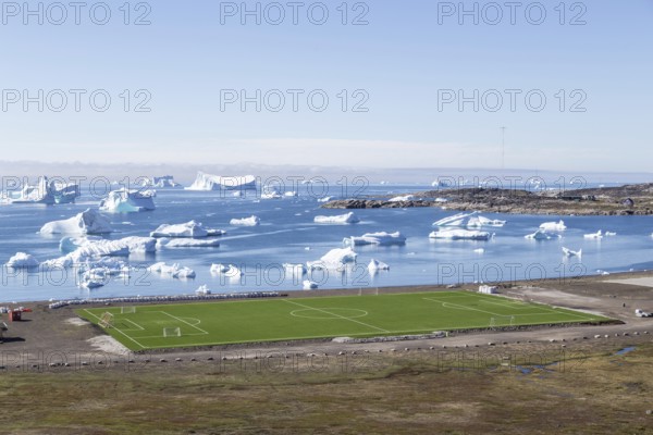 Qeqertarsuaq, Greenland, July 6, 2018: The local soccer field with icebergs in the background,