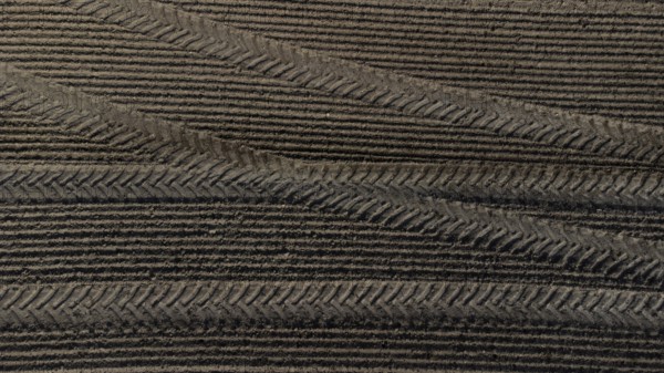 Tractor tyre tracks form an interesting pattern on a freshly cultivated field without vegetation,