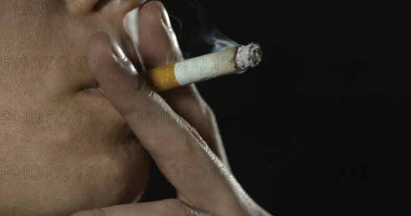 Woman smoking a Cigarette against Black Background