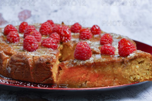 Homemade sweet potato, cake with raspberries and coconut flakes on a red plate