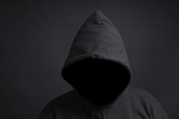 faceless person wearing black hoodie hiding face in shadow