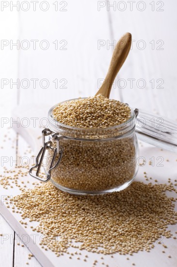 White quinoa seeds in a jar on white wooden table, closeup
